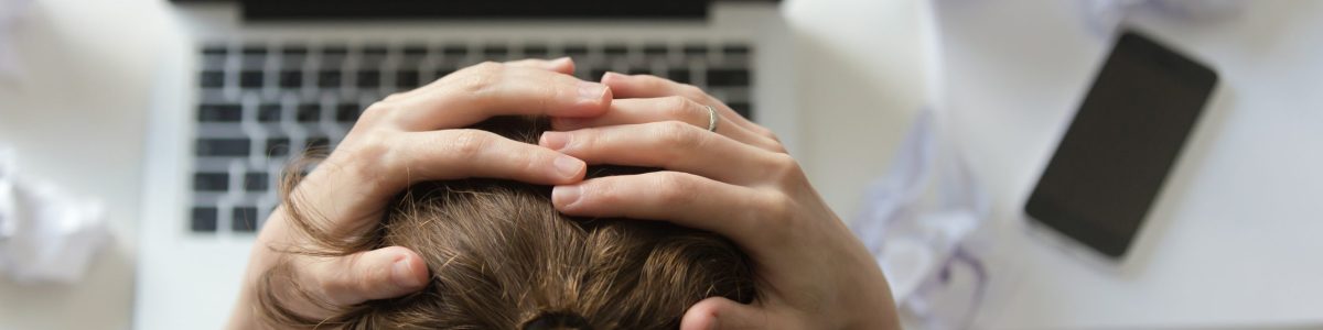 Top view portrait of a woman grabbing her head in despair at the desk near the laptop. Education, business concept photo. Lifestyle